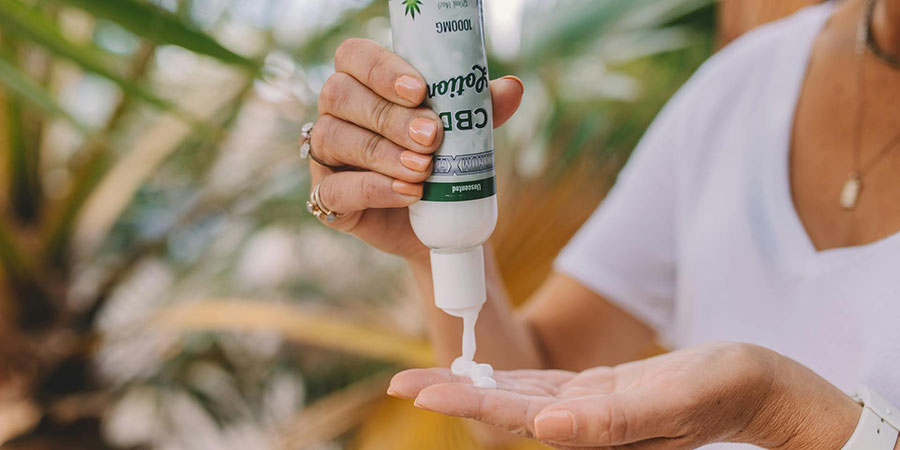 close up view of a person squeezing a bottle of CBD lotion and putting some of it on top of their palm
